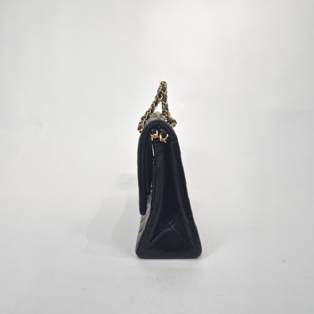 Black handbag with gold chain strap on a white background