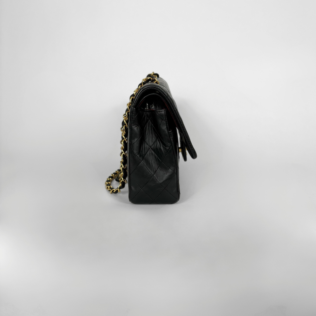 Black quilted Chanel shoulder bag with gold hardware on a white background