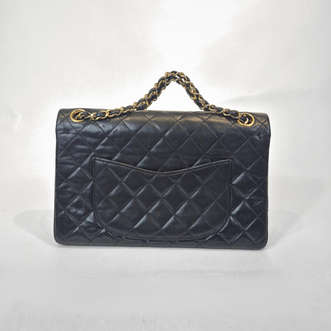 Black quilted handbag with gold chain handle on a white background