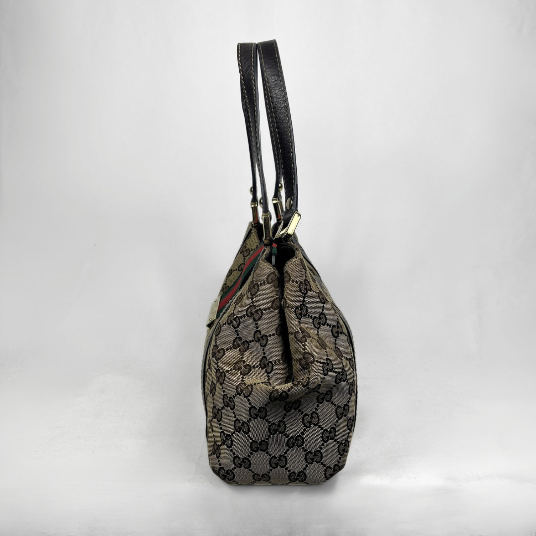A vintage Gucci bucket bag in brown GG Supreme canvas with black leather trim and handles, shown from the side against a white studio background.