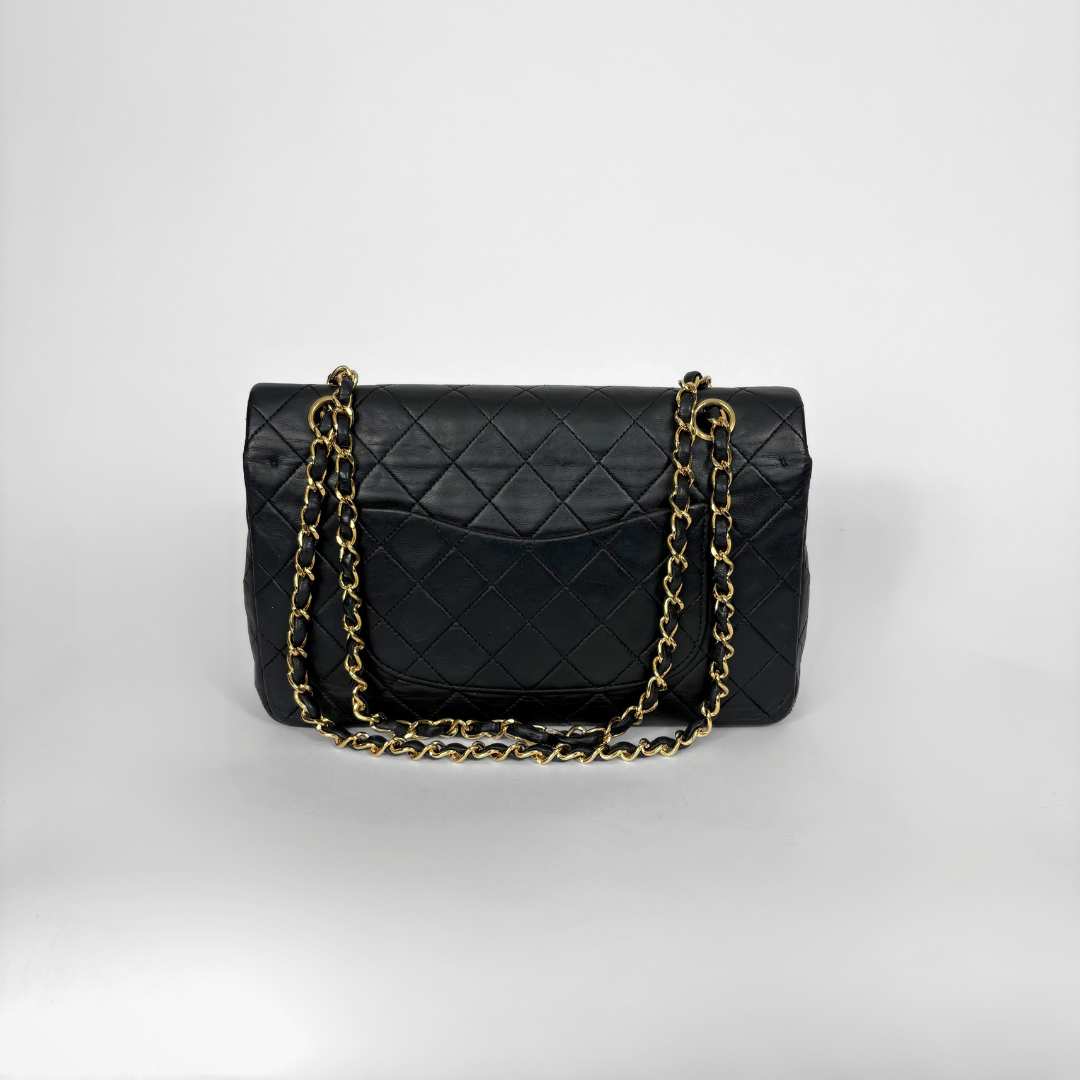 Black quilted Chanel shoulder bag with gold hardware on a white background