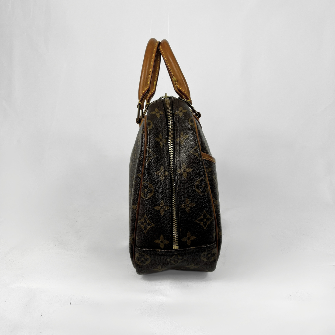 A Louis Vuitton monogram canvas handbag shown from the side against a white studio background, featuring dark brown coated canvas with the classic tan monogram pattern and tan leather handles.