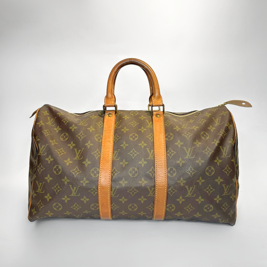 Brown travel bag with tan leather handles and trim on a light gray background