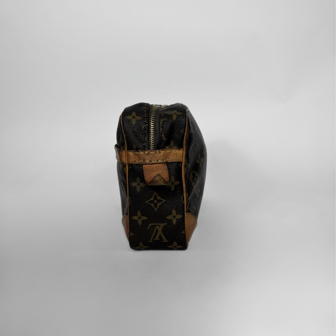 A Louis Vuitton monogram canvas toiletry bag in dark brown and tan, shown from the back against a neutral light gray background.