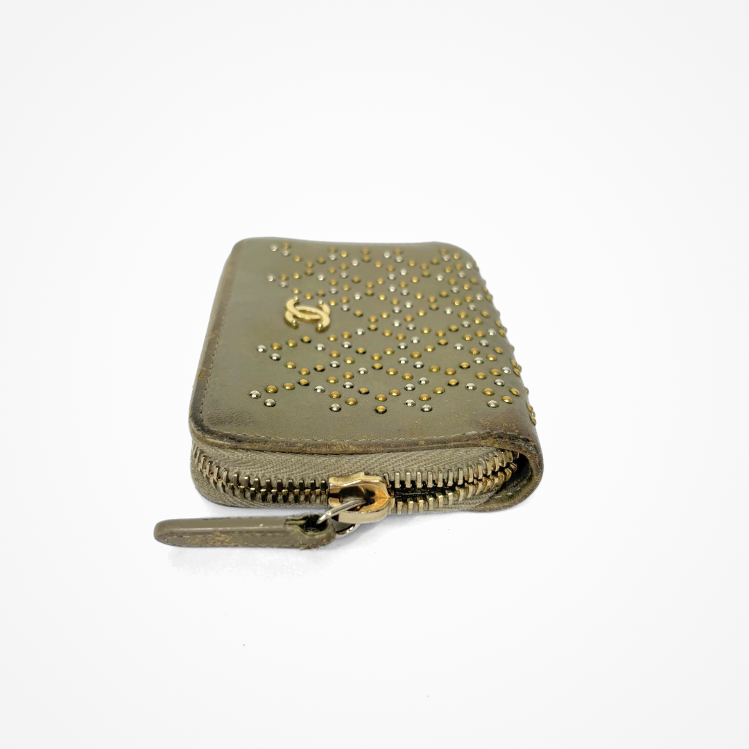 Beige Chanel wallet with gold studs on a white background
