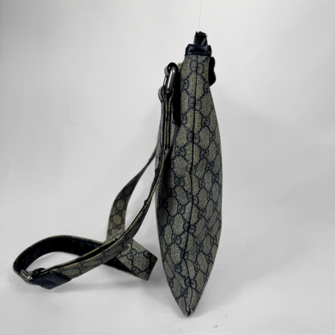 Gucci GG Supreme Web Flat Messenger bag in signature monogram canvas with green and red Web detailing and leather trims, displayed on a light grey background.