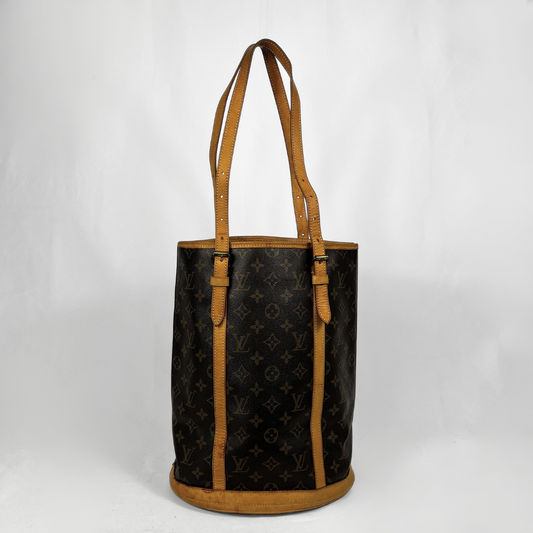 A Louis Vuitton monogram canvas tote bag with tan leather trim and shoulder straps, photographed against a plain white studio background.