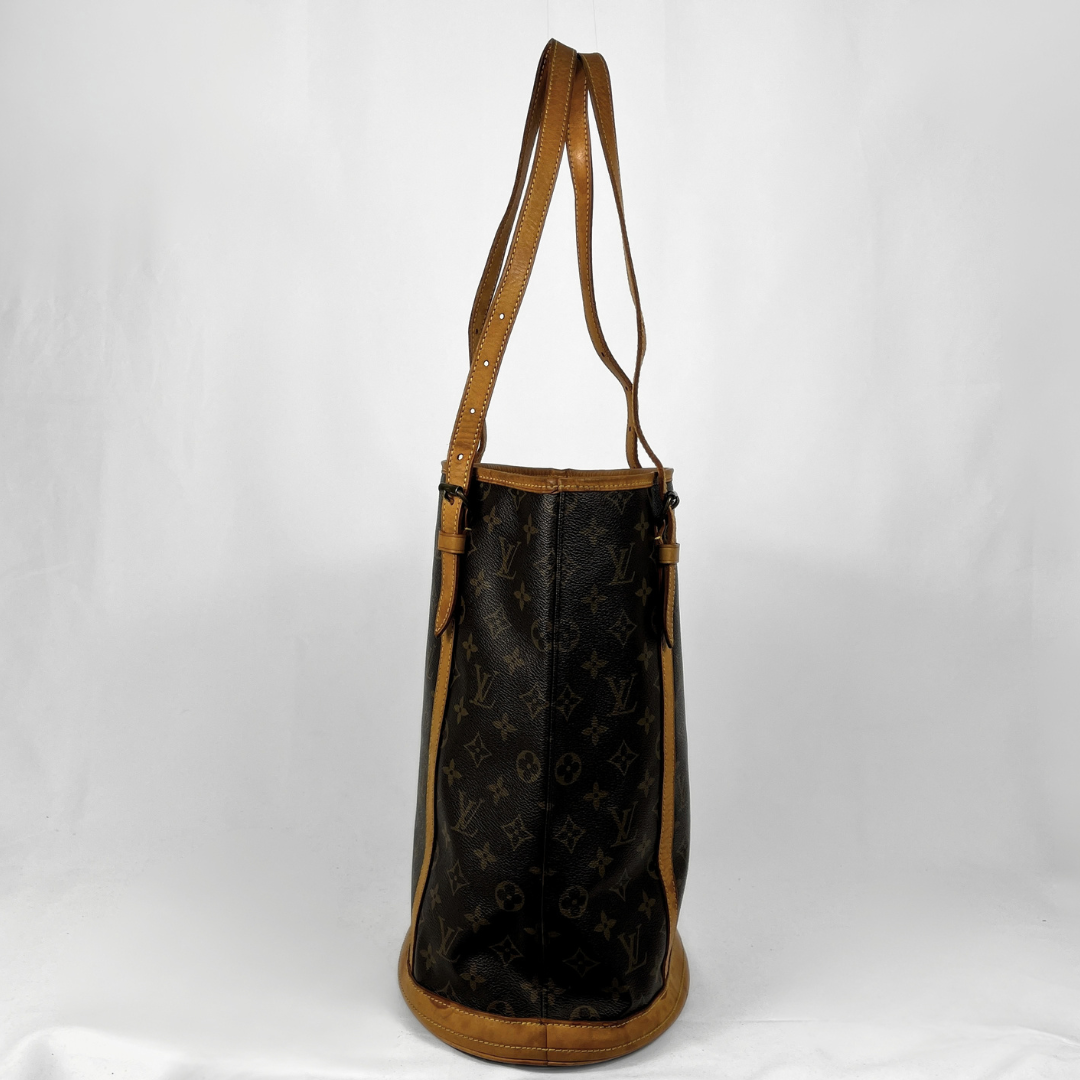 A Louis Vuitton Neverfull tote bag in dark brown monogram canvas with tan leather trim and shoulder straps, shown against a white fabric backdrop.