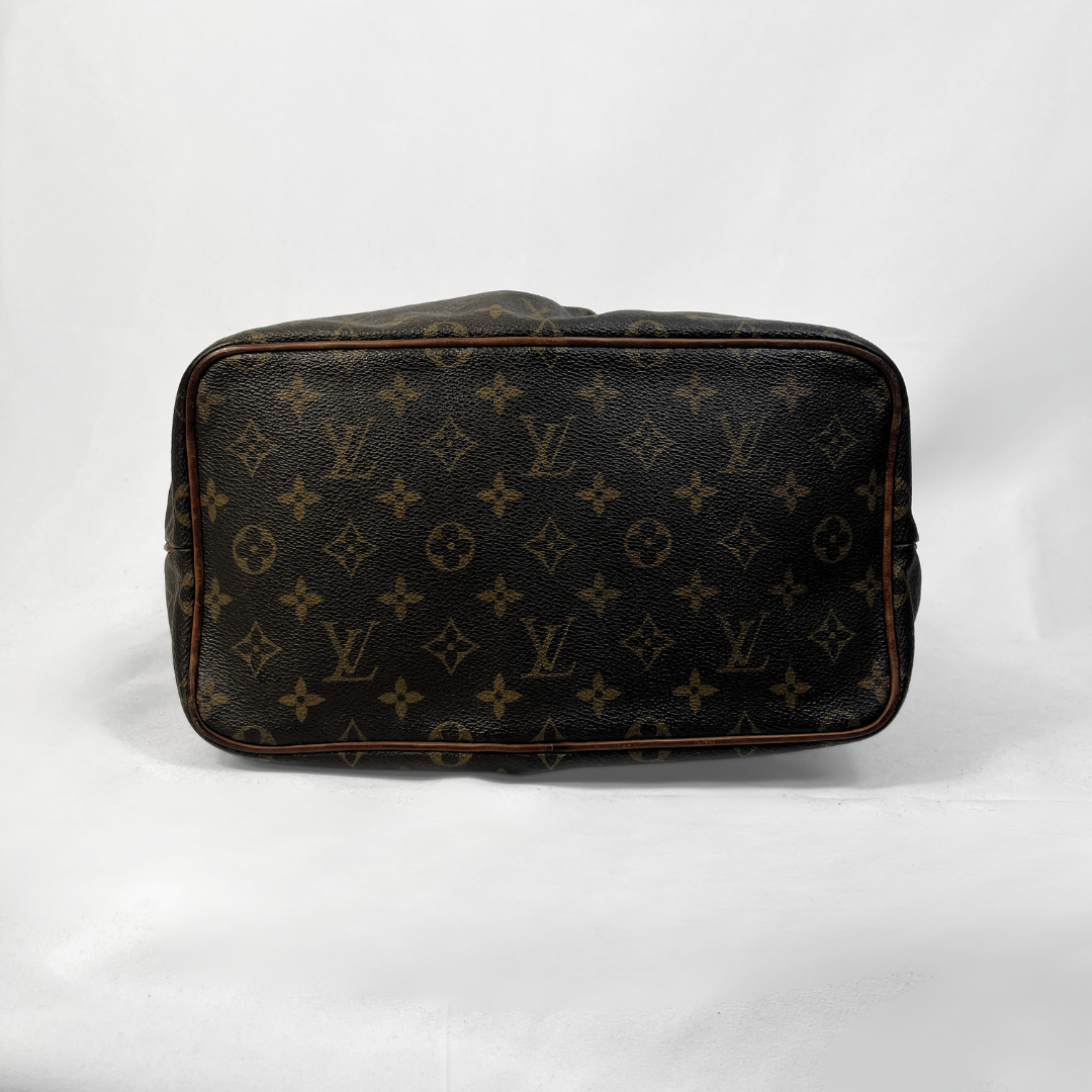 A Louis Vuitton monogram canvas toiletry bag shown from the bottom, featuring the classic dark brown and tan monogram pattern on a white background.