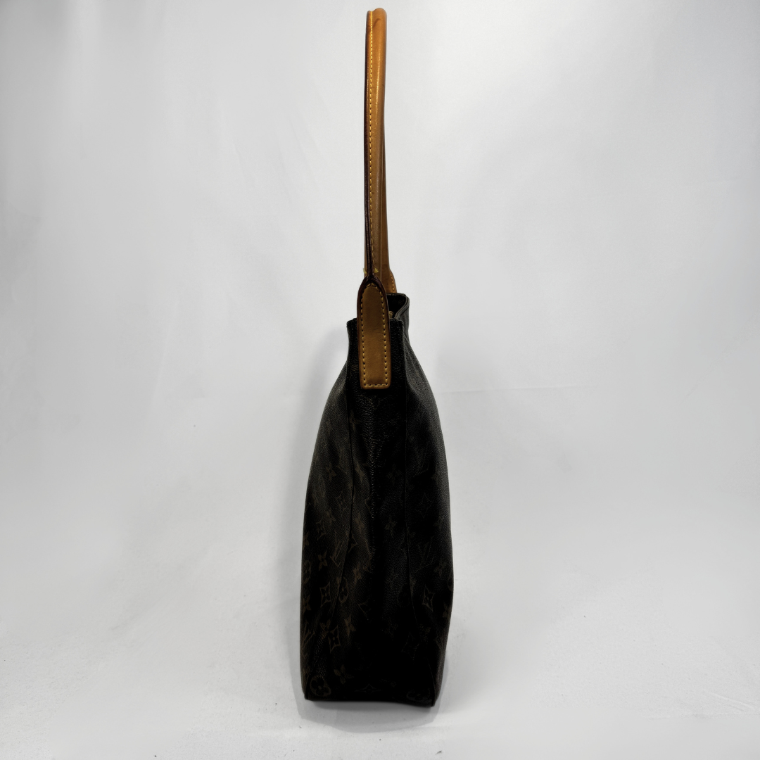 A dark brown Louis Vuitton monogram canvas tote bag with a tan leather shoulder strap, shown from a side profile view against a white studio background.