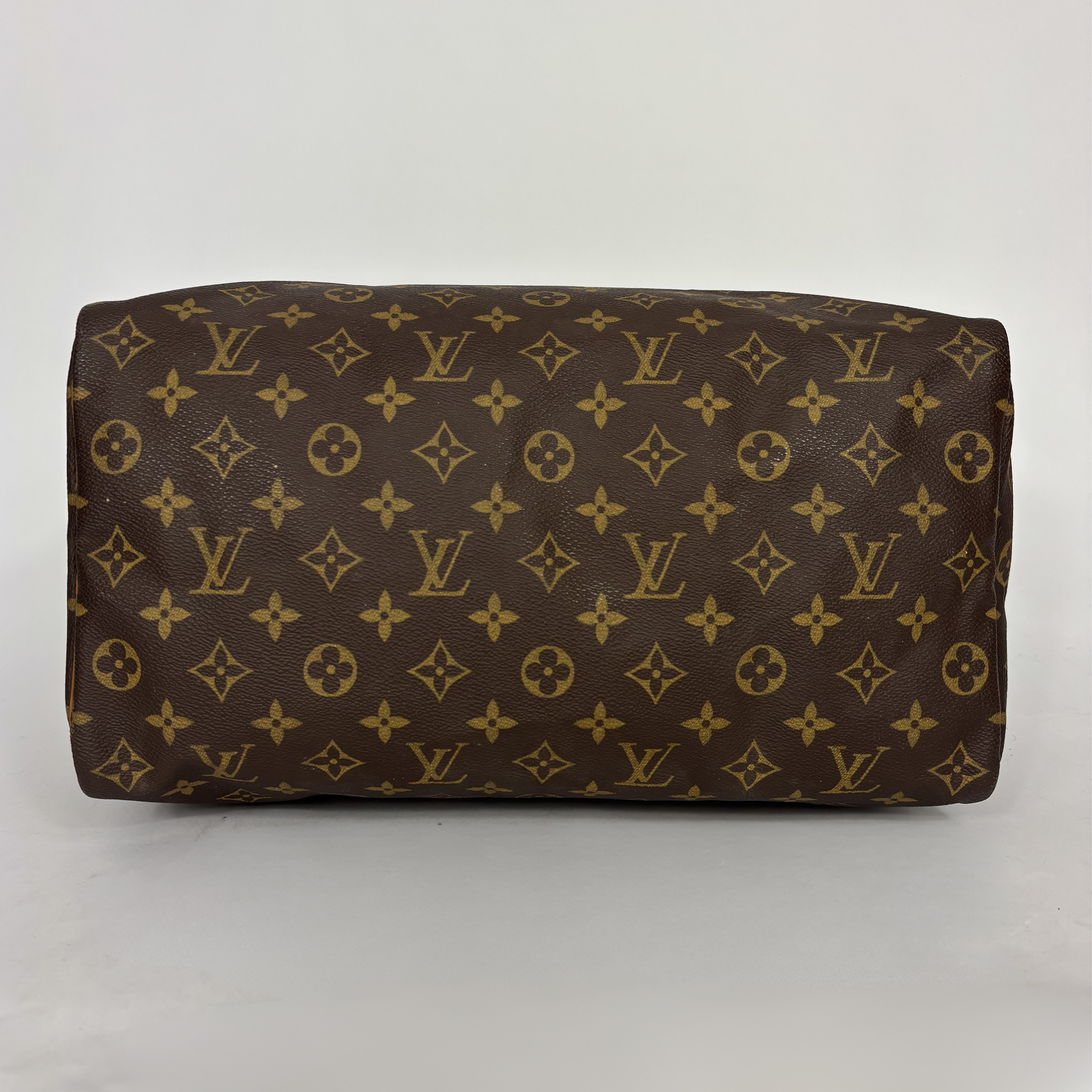 Brown leather bag with gold monogram pattern on a white background
