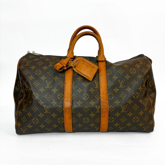 Louis Vuitton monogram handbag with brown leather straps on a white background