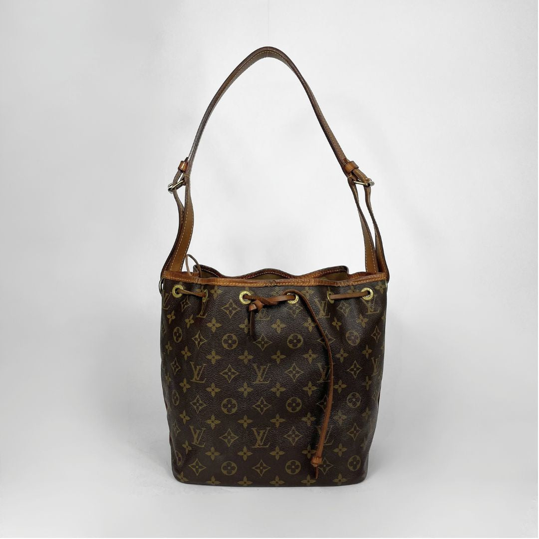 A Louis Vuitton monogram canvas bucket bag with brown leather trim and shoulder strap, shown against a light gray background.