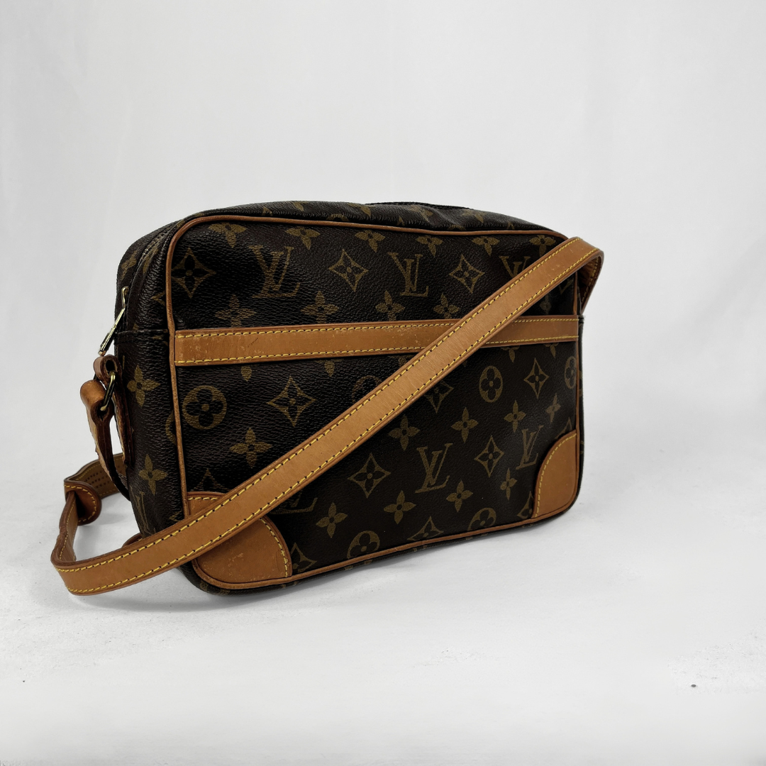 Louis Vuitton monogram canvas shoulder bag with tan leather trim and strap, shown on a white studio background.