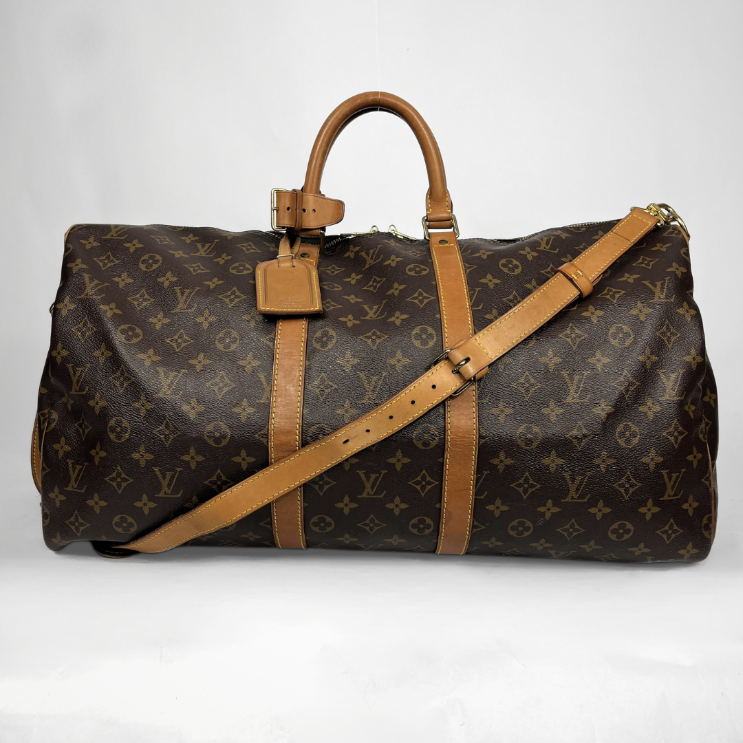 A Louis Vuitton monogram canvas duffel bag with tan leather handles, trim, and a matching shoulder strap, photographed against a plain light background.