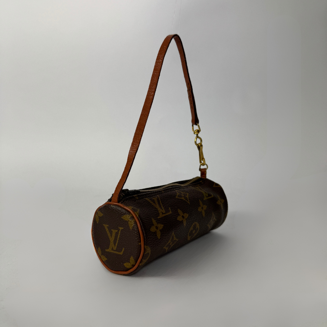 Louis Vuitton monogram canvas cylindrical shoulder bag with a brown leather strap and gold-tone hardware, photographed on a light gray studio background.