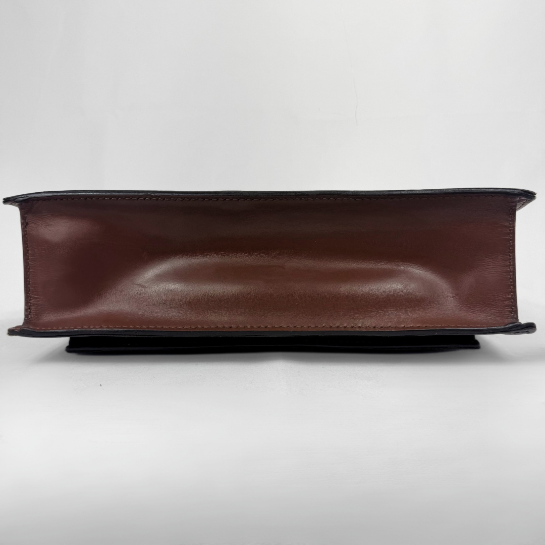 A brown leather book-style clutch or wallet shown from the bottom edge, displaying its smooth leather interior and dark stitched edges, set against a plain light gray background.