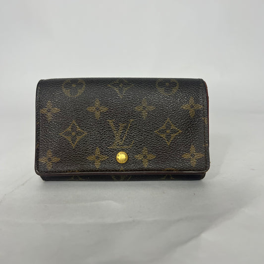 Louis Vuitton wallet with monogram pattern on a light gray background