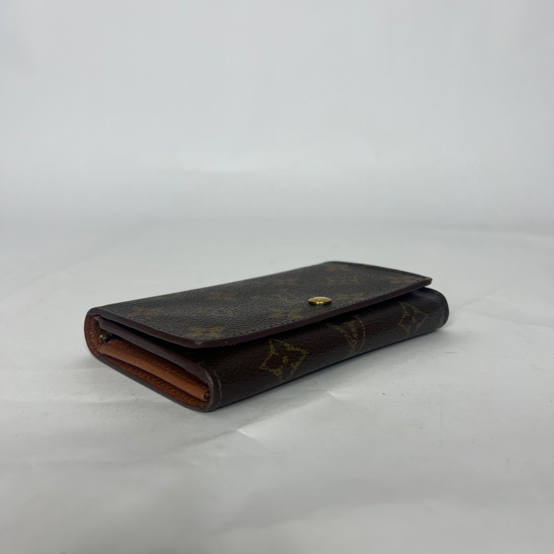 Brown leather wallet with gold accents on a white background