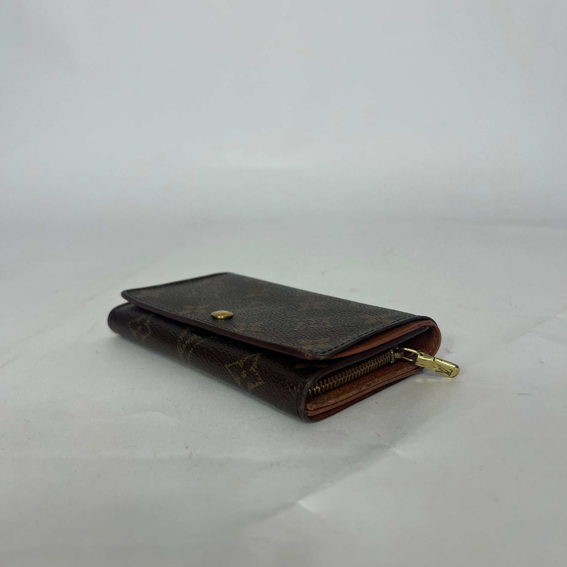Brown wallet with gold accents on a light gray background