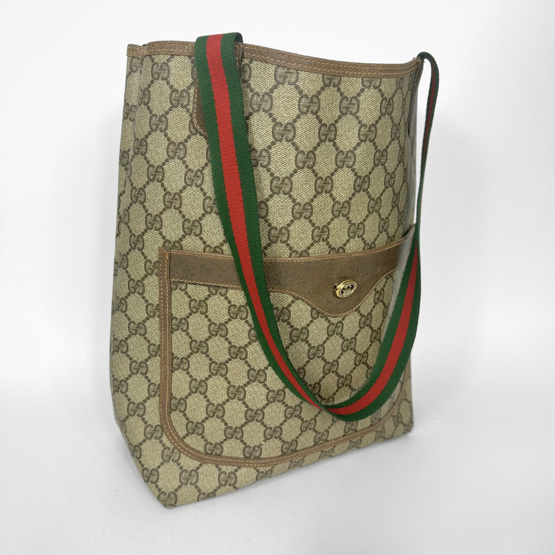 Designer tote bag with monogram pattern and red and green stripes on a light gray background